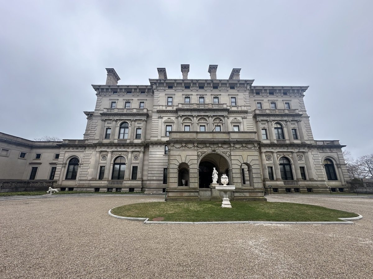 The Breakers facade — limestone exterior, five floors, fountain, gray sky, Newport Rhode Island