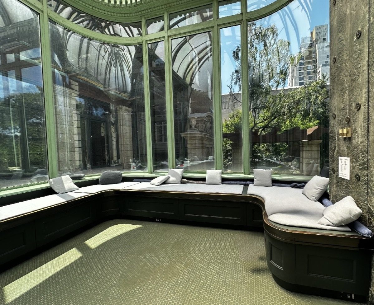 Carnegie Mansion conservatory — glass dome, green iron framework, cushioned window seats overlooking garden