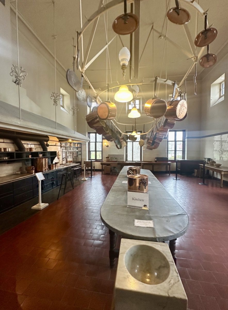 The Breakers kitchen — copper pots, cast iron range, zinc work table, terra cotta floor